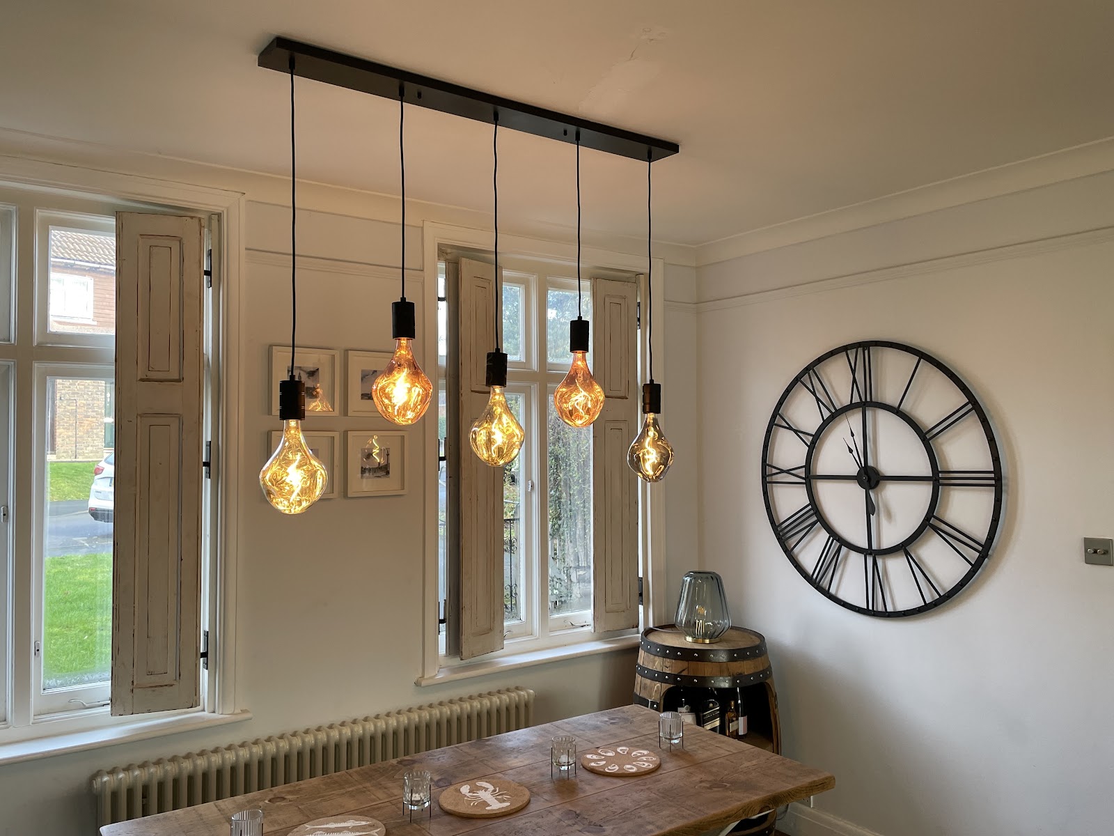 A dining room with a bar of filament pendant lights