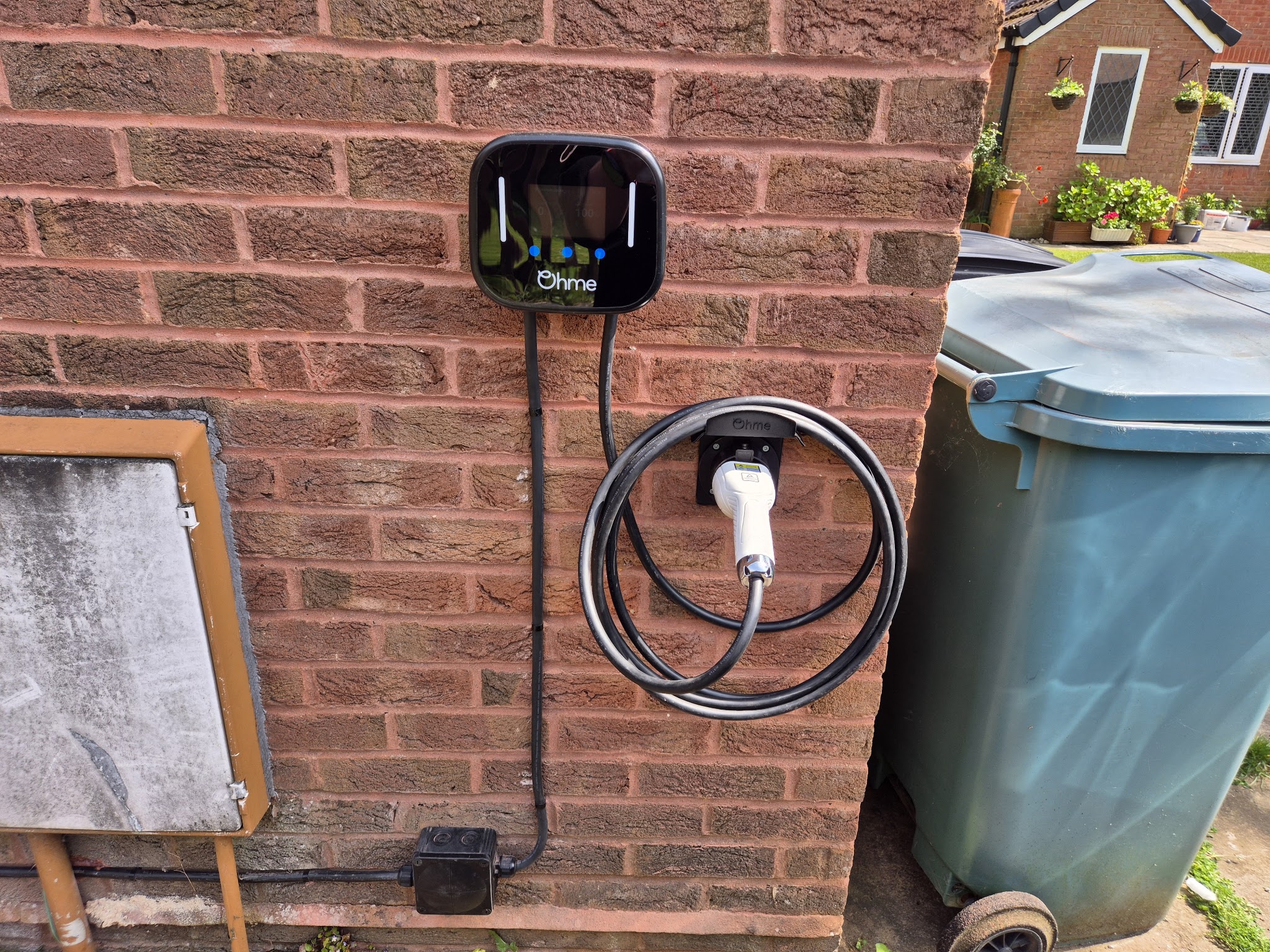 An Ohme charger fitted on a house wall with a neat cable run